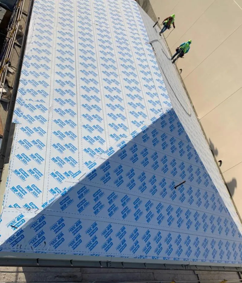 Professional roofers installing underlayment on a metal roof in East Lansing